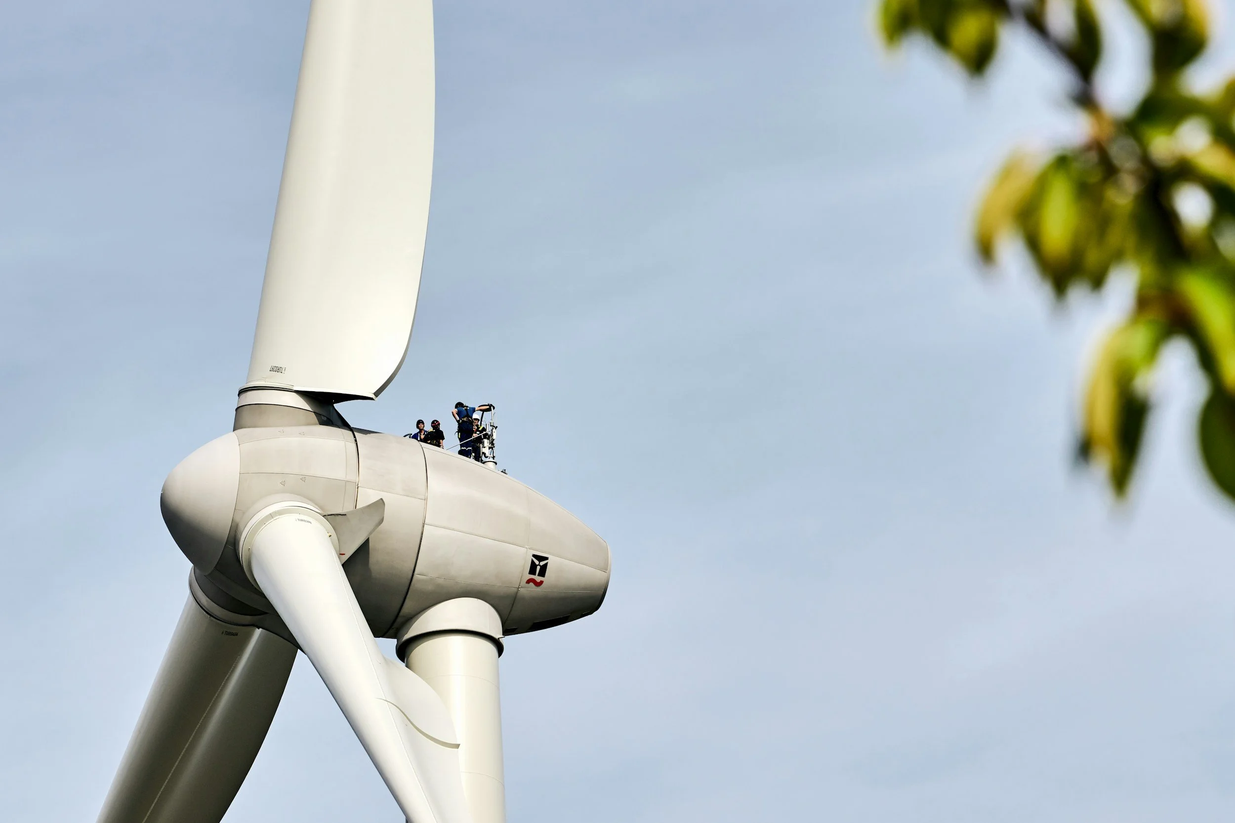 Menschen arbeiten auf einer Windkraftanlage in großer Höhe.