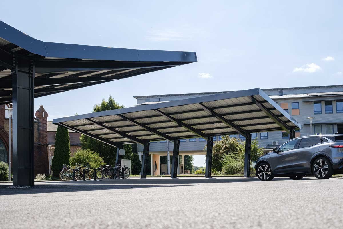 Mehrere solarbetriebene Parkdecks mit Fahrzeugen, Fahrrädern und Gebäuden im Hintergrund