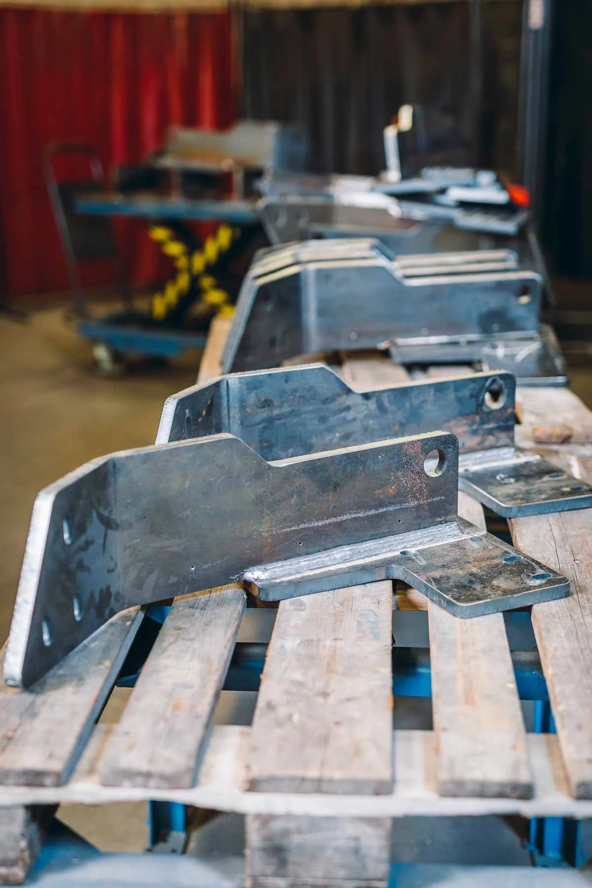 Brennraum aus Metall auf einem Holzgestell, im Hintergrund Schrauben und Werkzeuge, wahrscheinlich eine Werkstatt