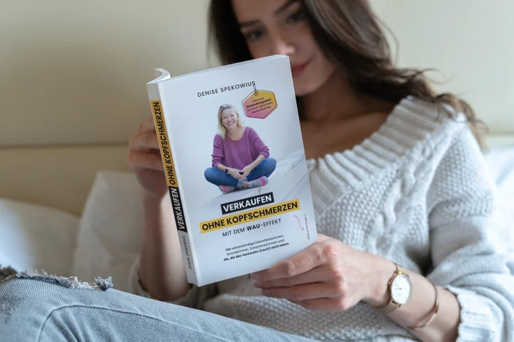 Frau liest das Buch „Verkaufen ohne Kopfschmerzen mit dem WAU-Effekt“ von Denise Spekowius