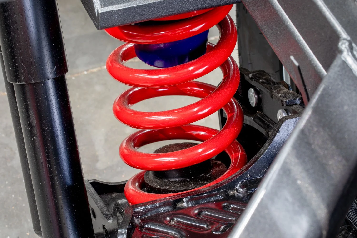 Close-up of a red coil spring on a vehicle suspension system.