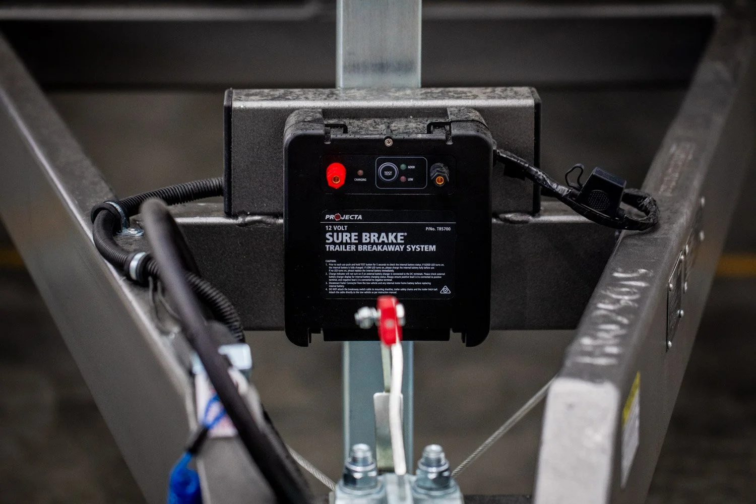 A 12-volt trailer brake system control box installed on a metal frame with wires connected to it.