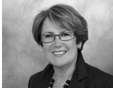 Schwarz-weiß Porträt einer Frau mit Brille, kurzen Haaren und einem schwarzen Blazer.