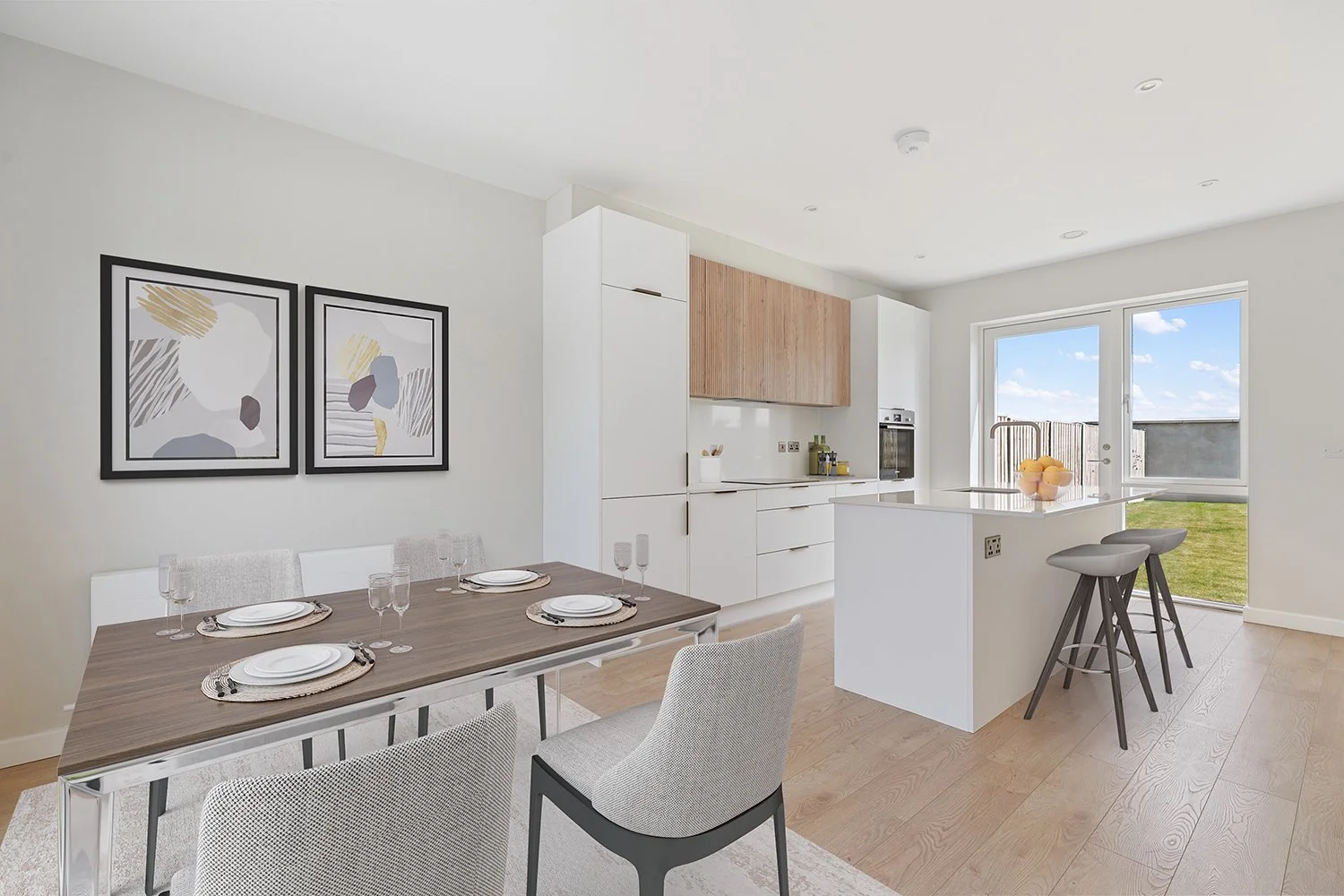 Modern open-plan kitchen and dining area with white cabinetry, light wood accents, a table set for four, and a sliding glass door leading to a yard.