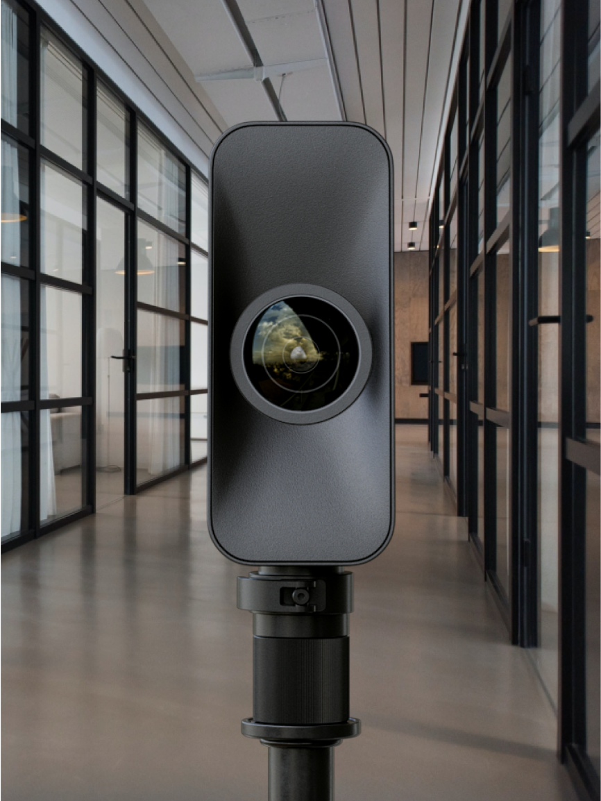A camera or projector device on a stand in a modern office or conference space with glass walls and wooden flooring.