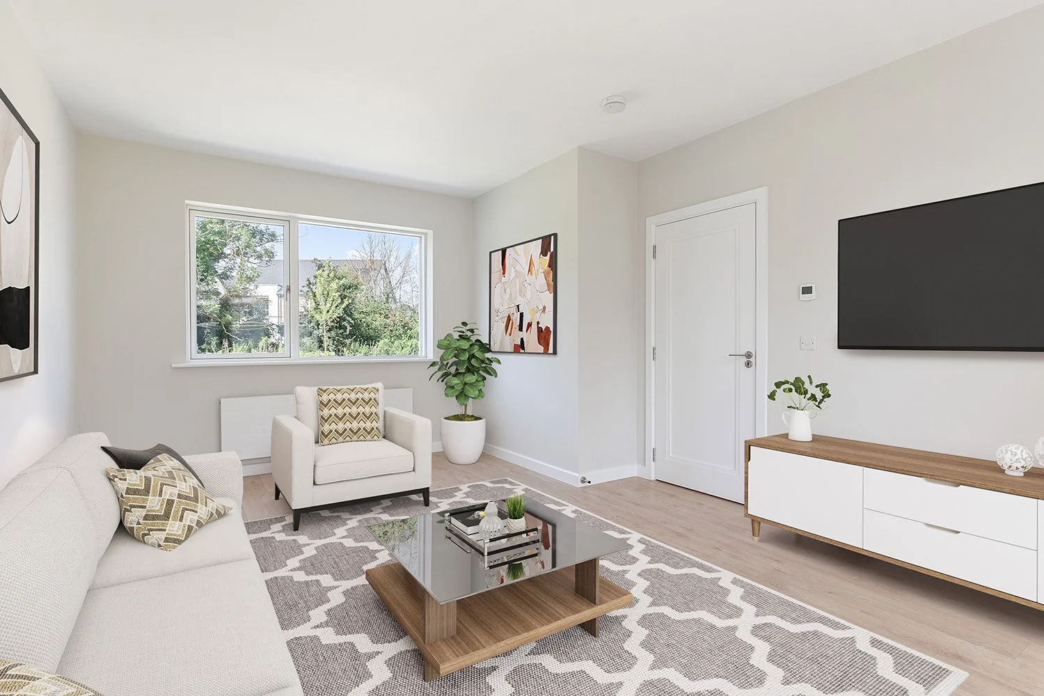 Modern living room with white sofa, white armchair, wooden coffee table, patterned rug, wall-mounted TV, abstract art, potted plant, large window showing garden view, minimalist decor.