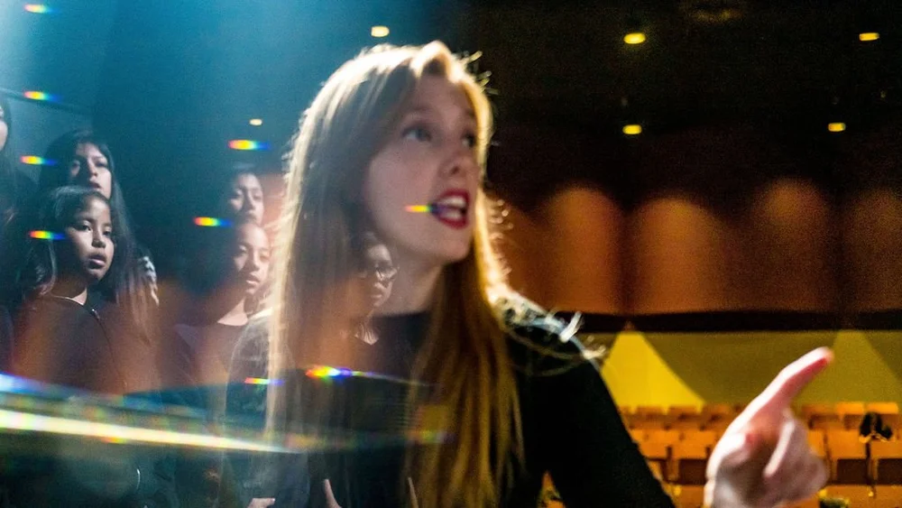 Greiner students singing amid colorful projected light.