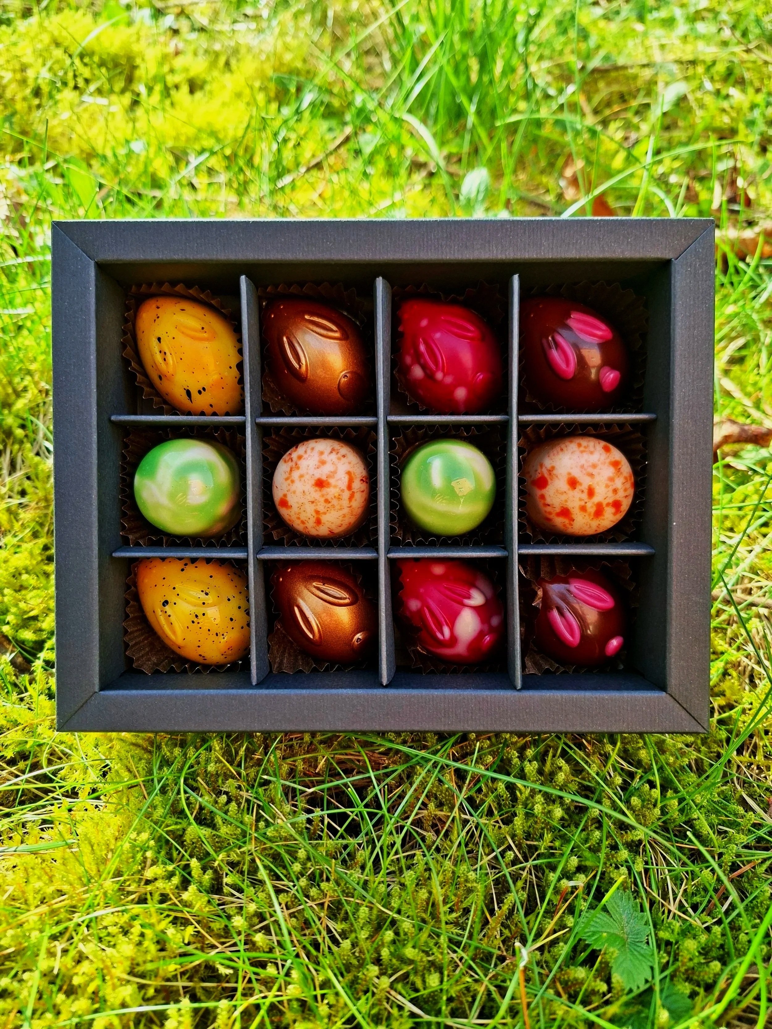 Bunte Hasenpralinen und bunte Pralinen in schwarzer Box