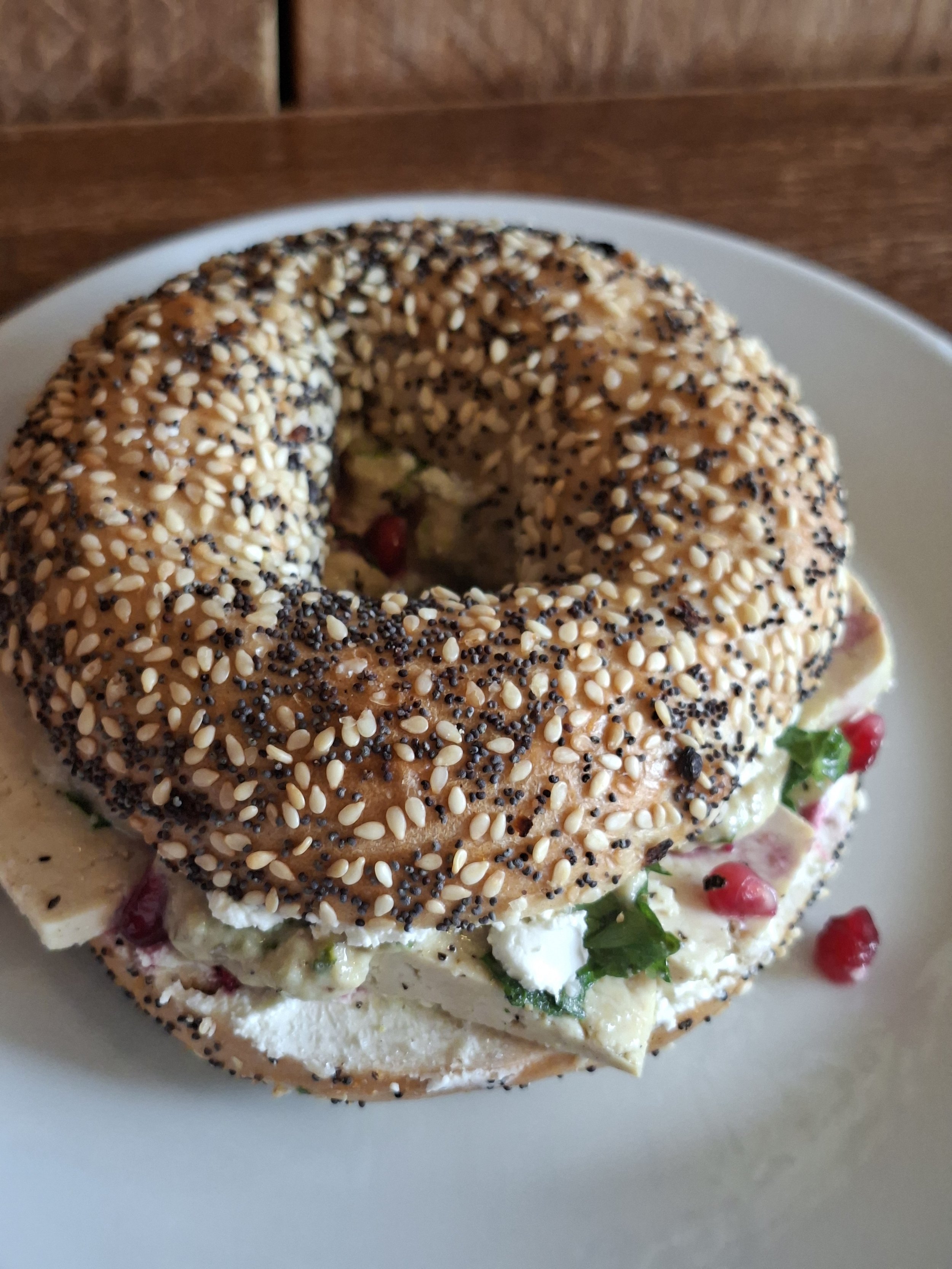 Veganer Bagel mit Baba Ganoush, eingelegtem Zitronen Tofu, Petersilie und Granatapfelkernen