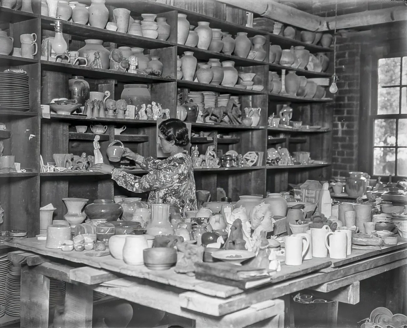 Woman examines a figurine and pot at Pewabic Pottery in Detroit, Michigan, date unknown. Photo from the Burton Historical Collection, Detroit Public Library. Retouching by Helmut Ziewers.