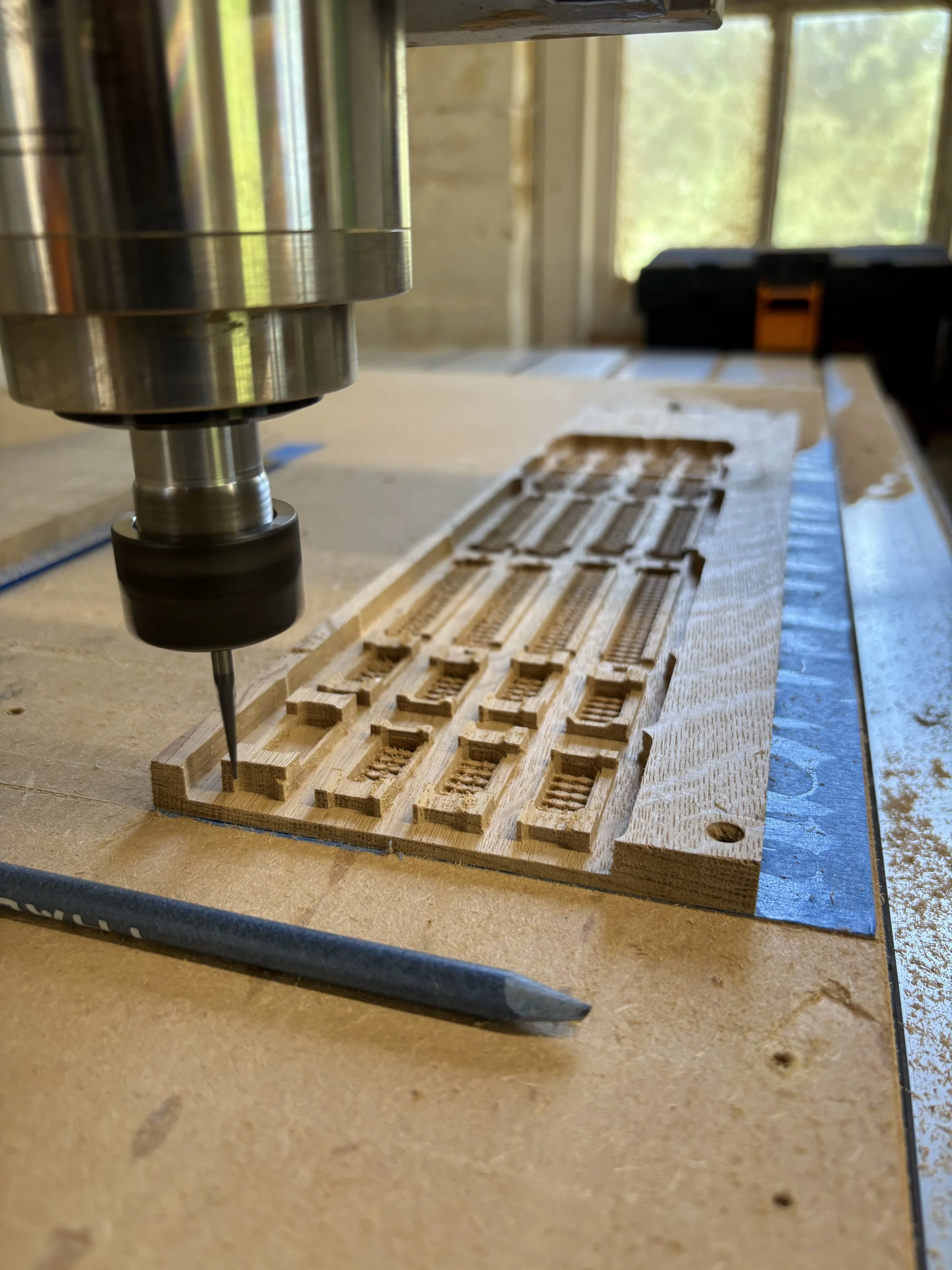 A CNC machine carving a detailed wooden scale model of a train.