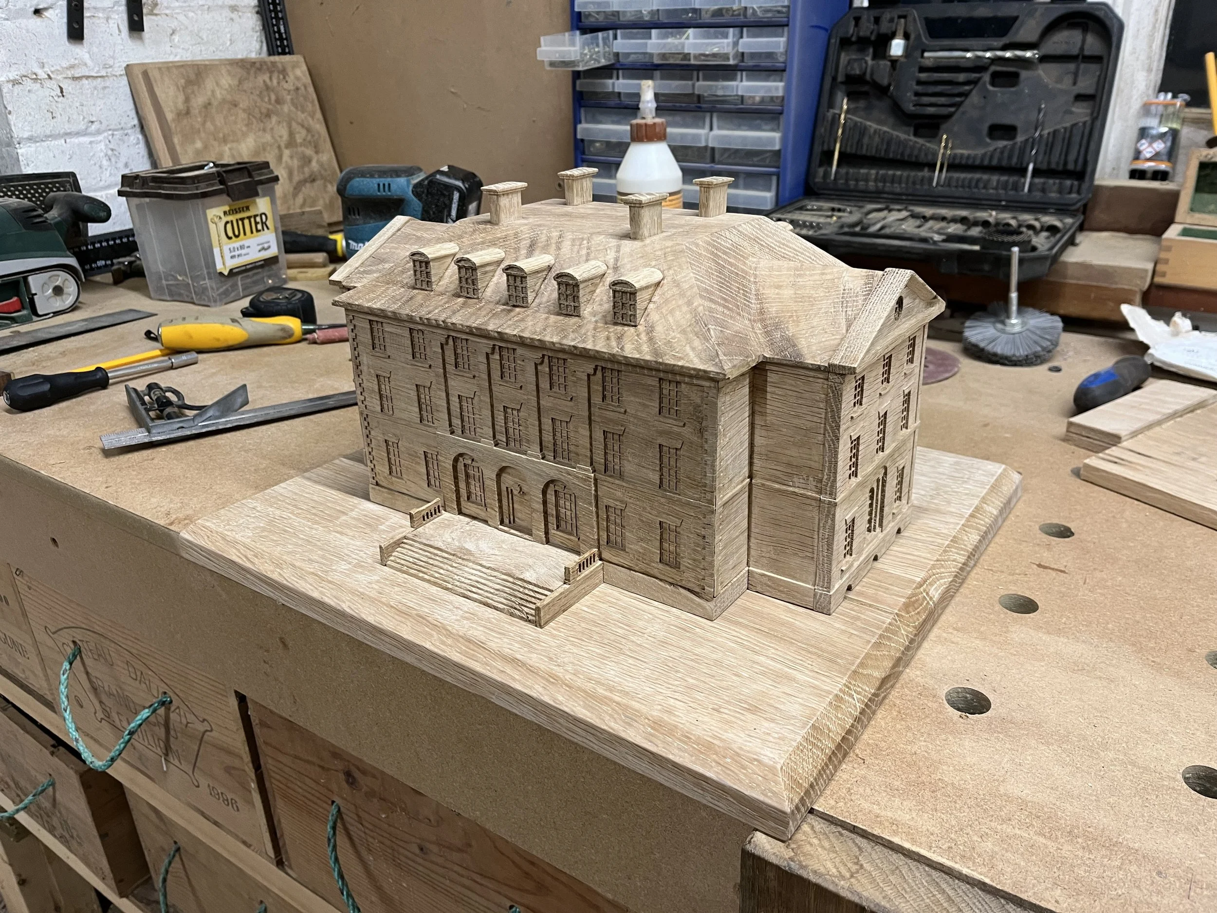 Wooden miniature model of a building on a workbench in a woodworking shop