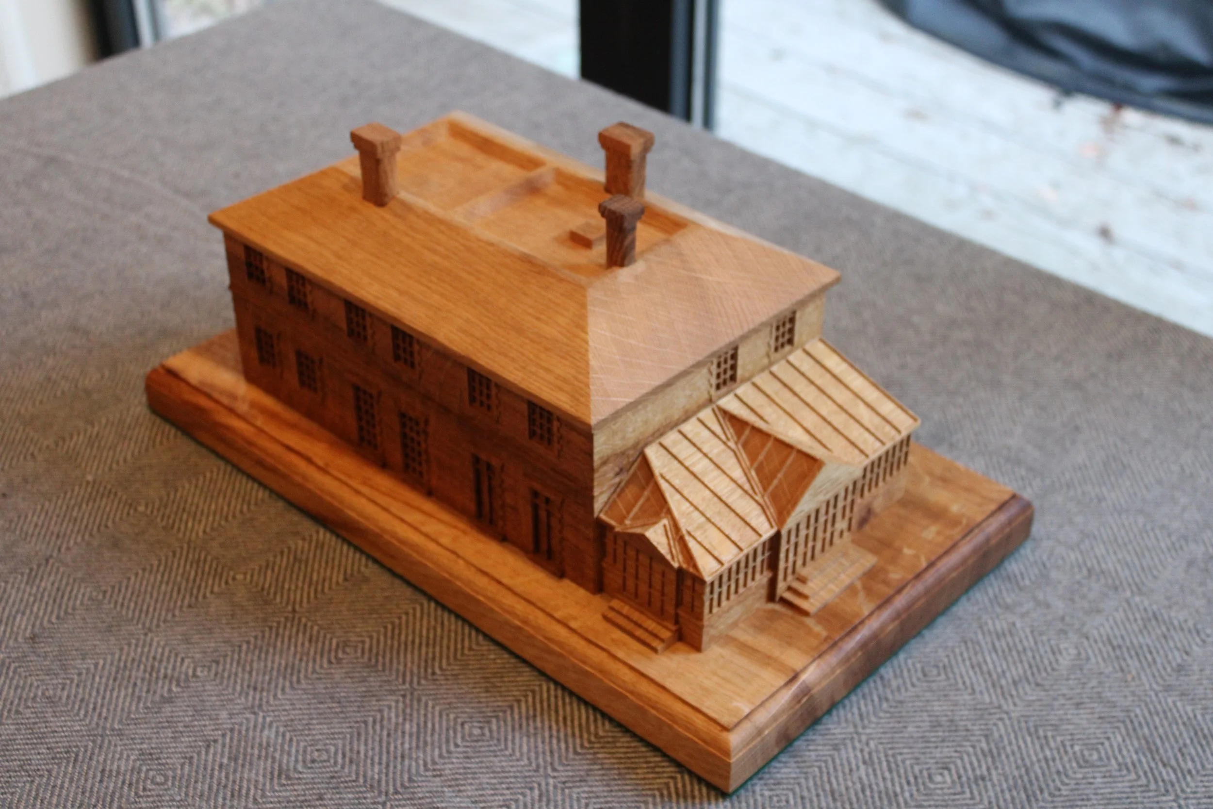 Wooden architectural model of a house on a table.