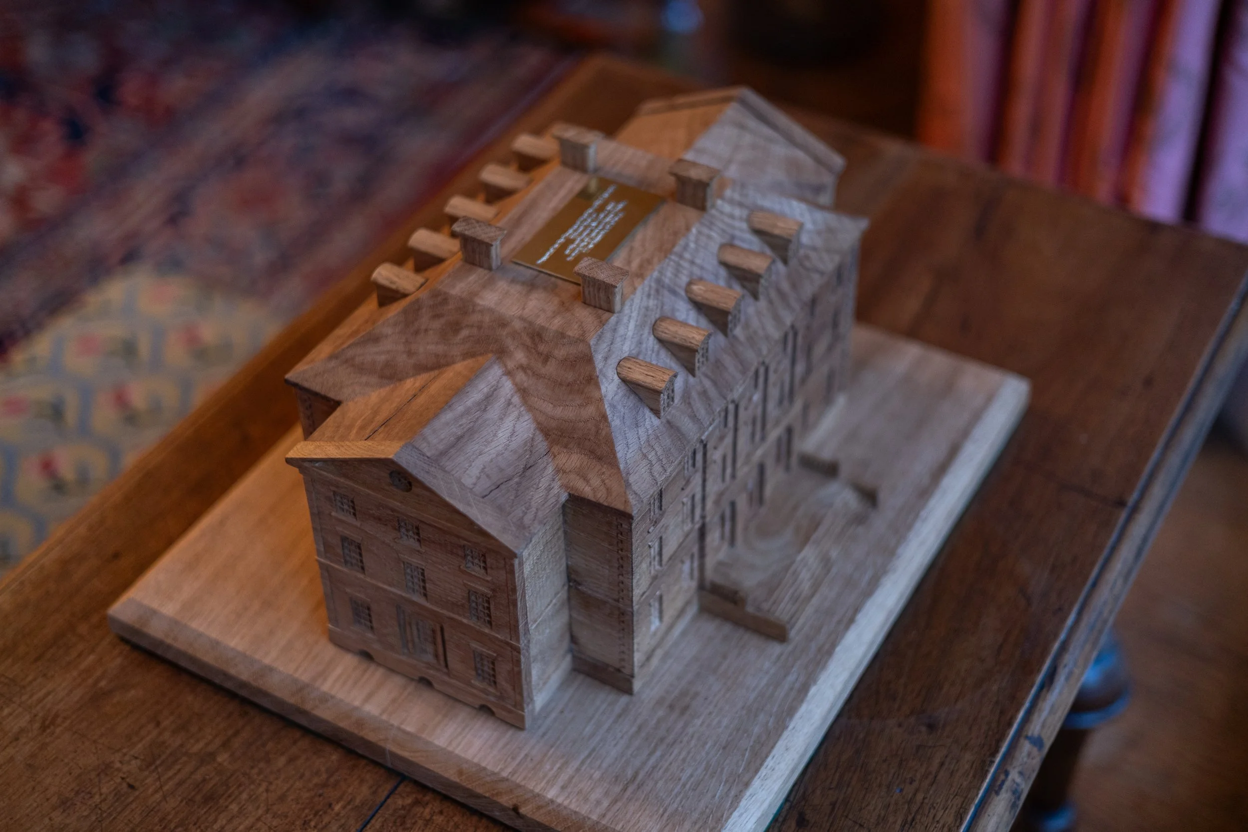 A detailed wooden architectural model of a historic building or university campus on a wooden table.