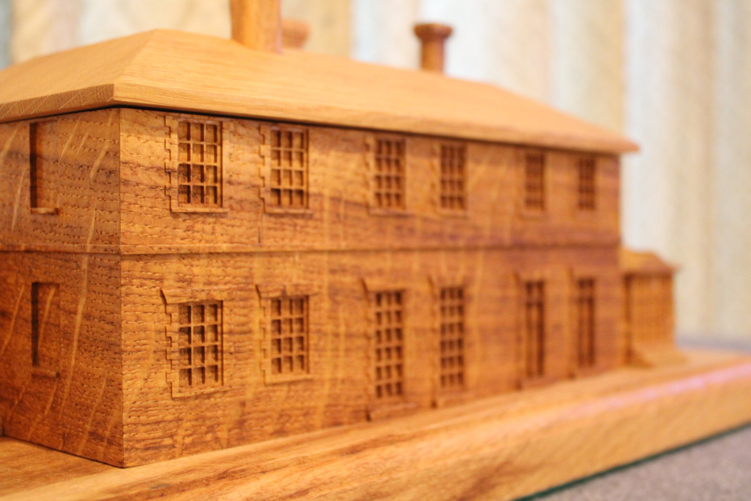A detailed wooden model of a multi-story building with small window openings.