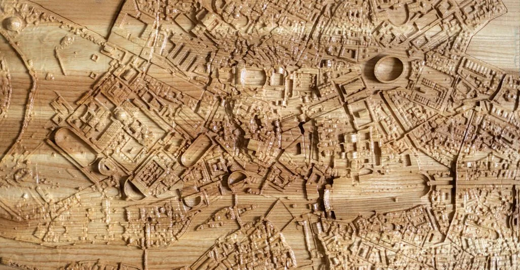 A detailed wooden map of a city with roads, buildings, and landmarks carved into the wood surface.