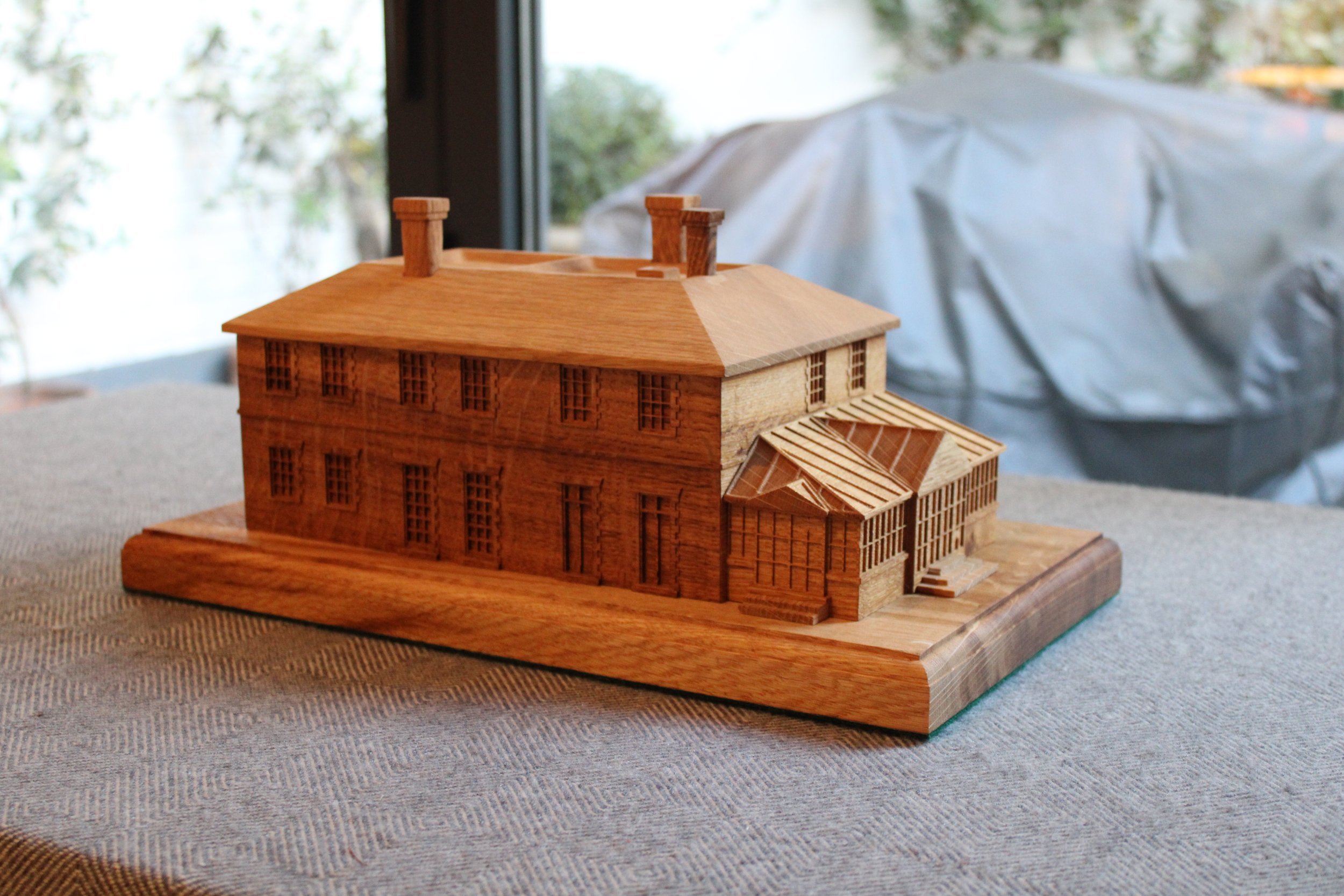 Wooden architectural model of a house on a table.
