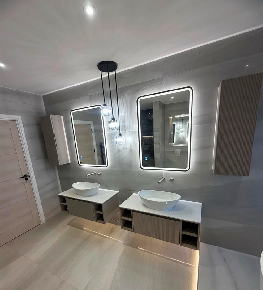 Луксозна баня с двойна мивка, дизайнерски LED огледала и сив широкоформатен гранитогрес от ПДД луксозно строителство.  Modern luxury bathroom with double vessel sinks, backlit LED mirrors, and large-format grey tiles by PDD Luxury.