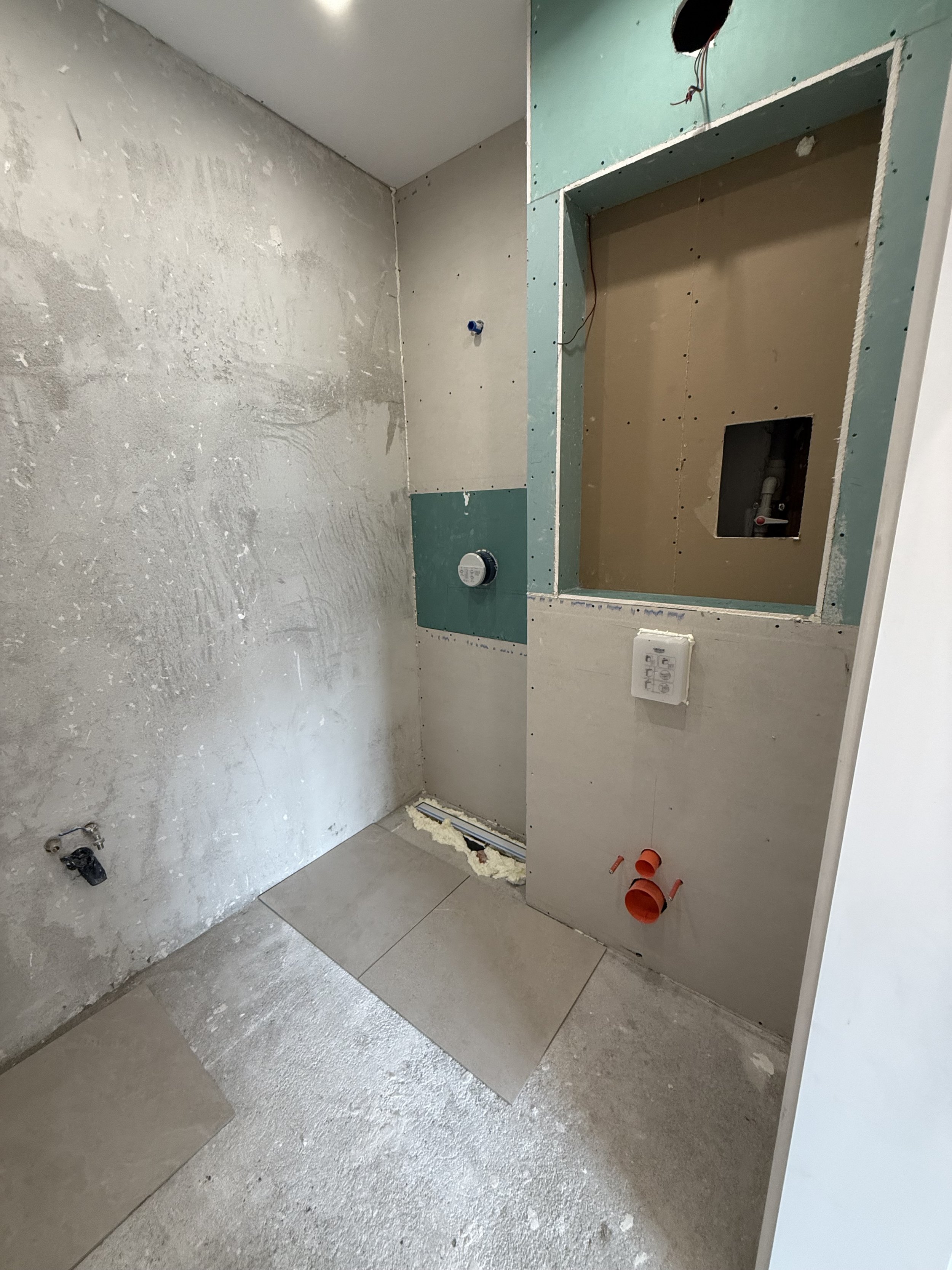 Баня съвременен стил с гранитогрес, имитиращ мрамор, акцентна стена с плочки с дървесен патерн, окачена тоалетна и скрито LED осветление.