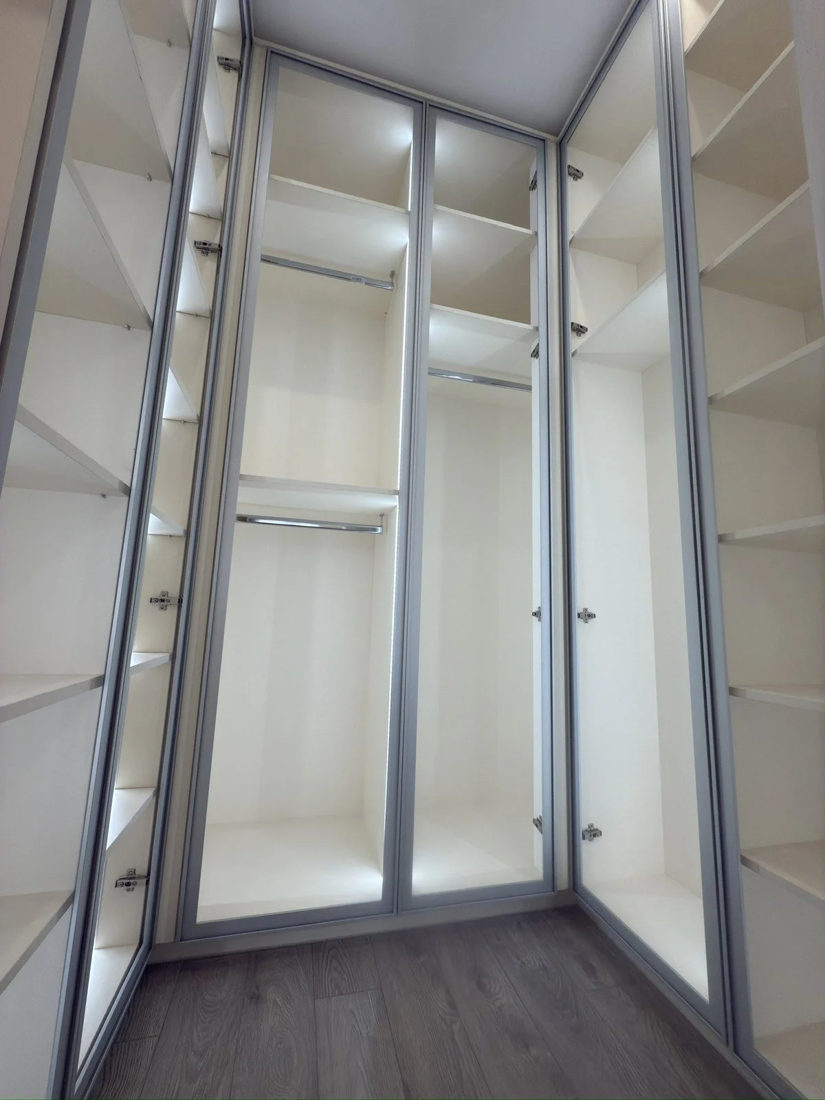 Професионално изграден гардероб с алуминиеви профили, стъклени витрини и автоматично вътрешно осветление на рафтовете.