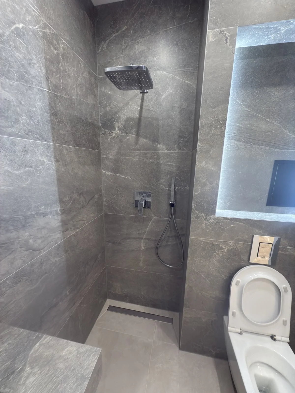 Луксозна душ зона с вградена смесителна система, пита тип „дъжд“ и линеен сифон.