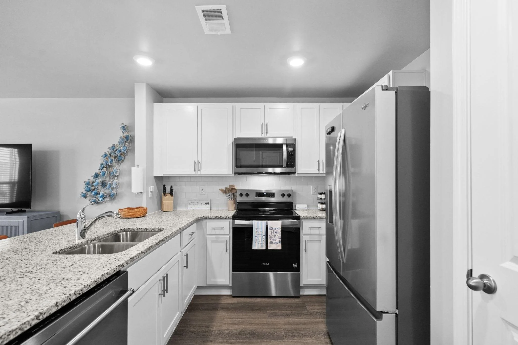 Modern kitchen with white cabinets, stainless steel appliances, granite countertops, and a double sink.