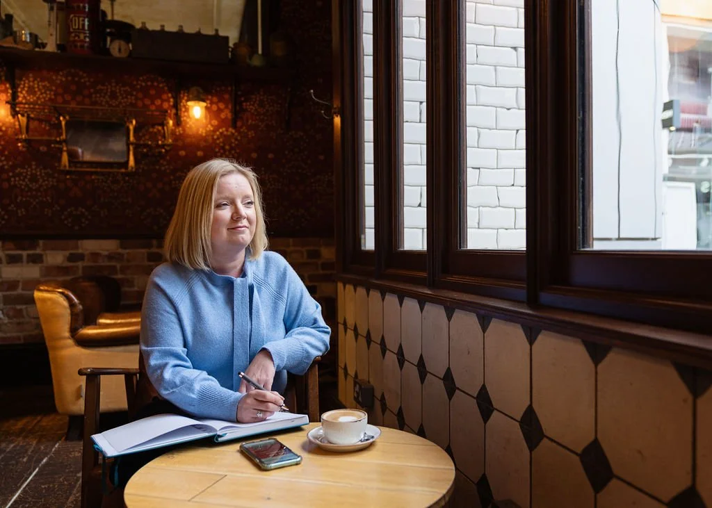 Woman sitting at a table writing in a notebook