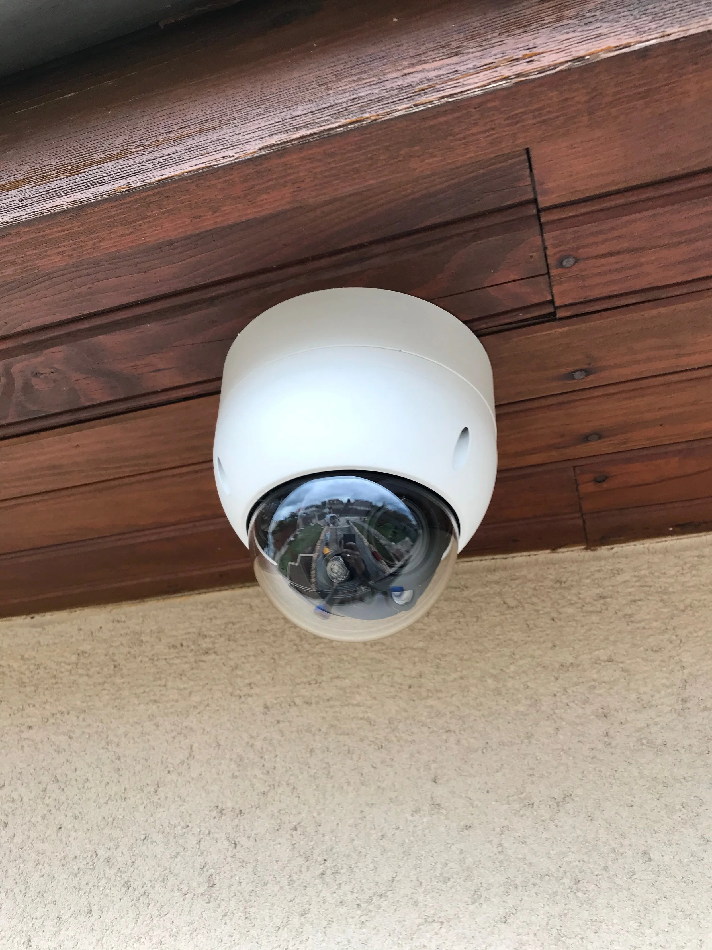 Caméra de surveillance installée sous un auvent en bois.