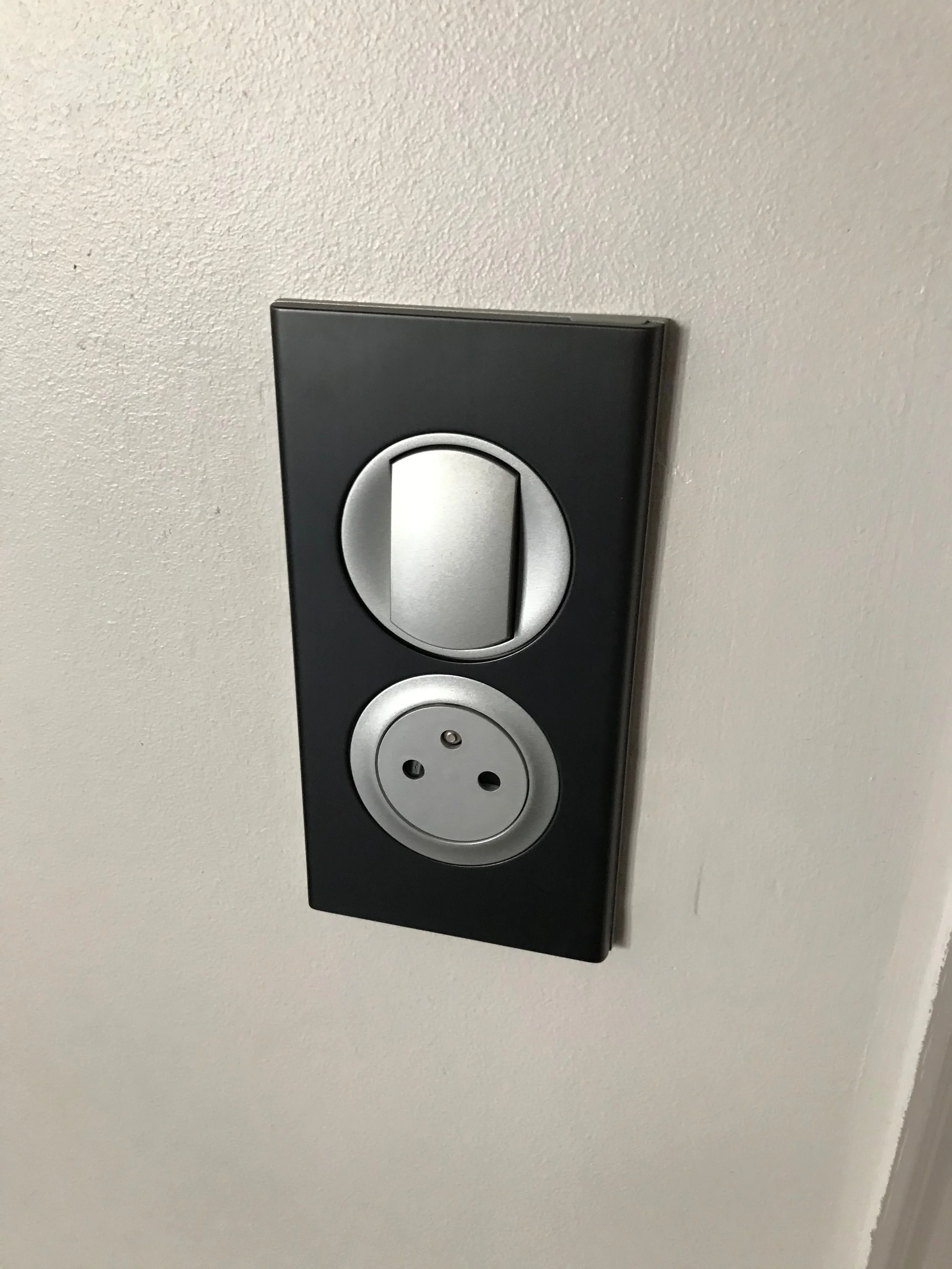Prise électrique avec interrupteur sur un mur blanc.