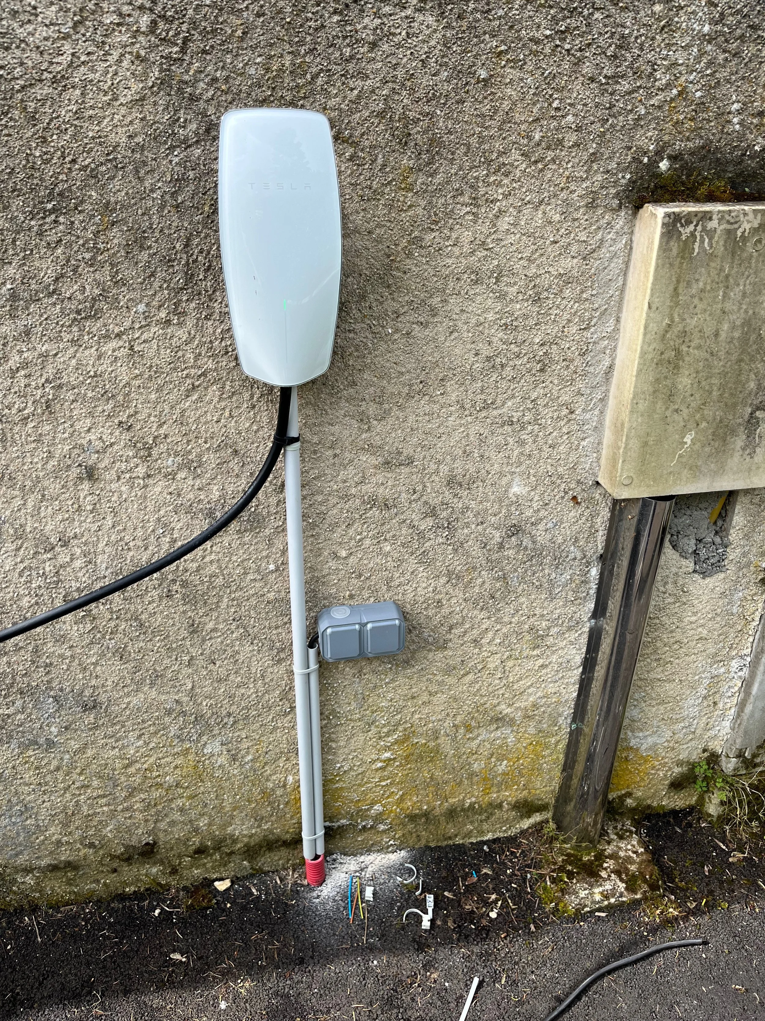 Panneau électrique extérieur et antenne Tesla sur un mur en béton.