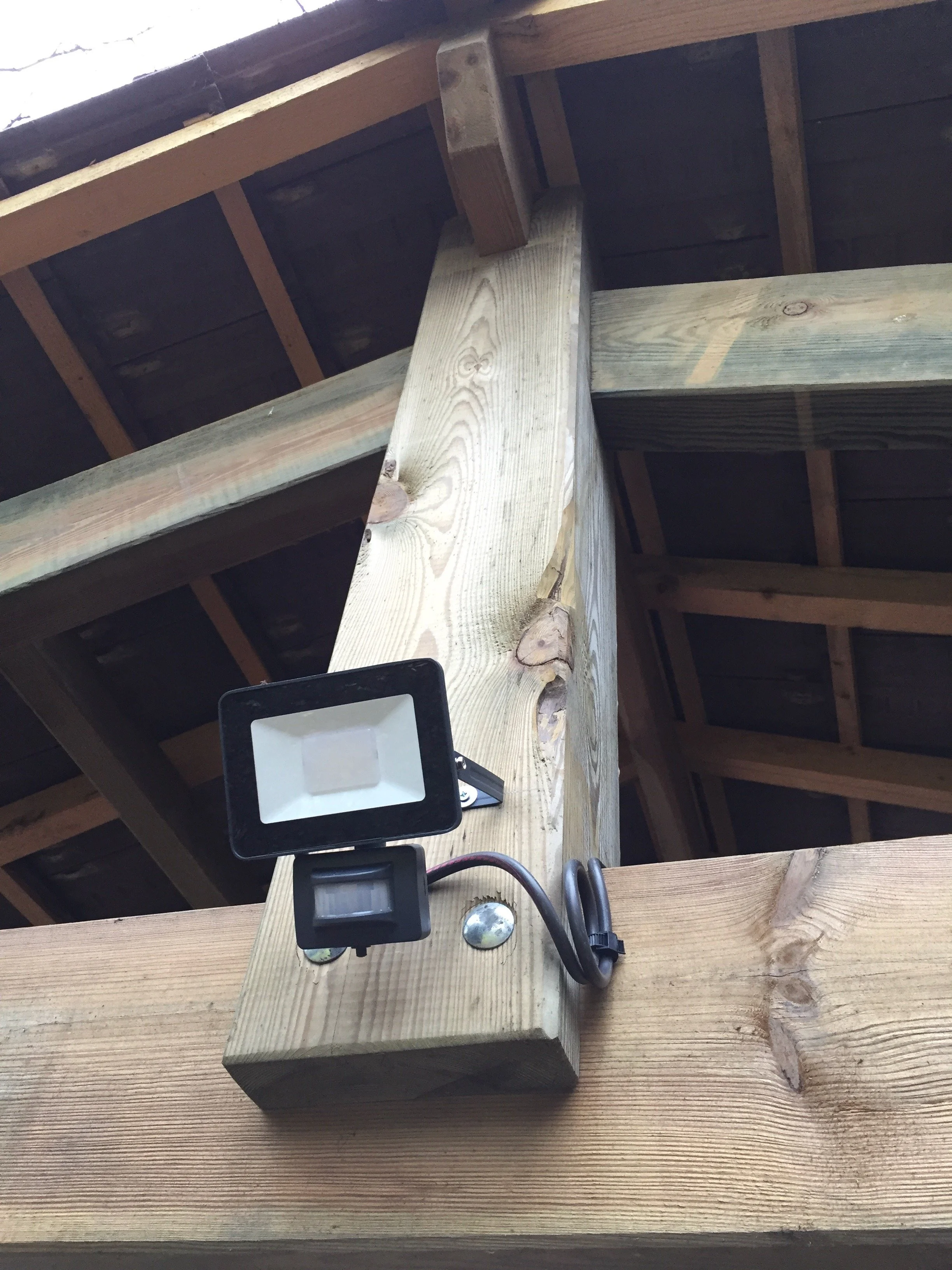 Une lampe LED montée sur une poutre en bois dans une structure de toiture en bois.