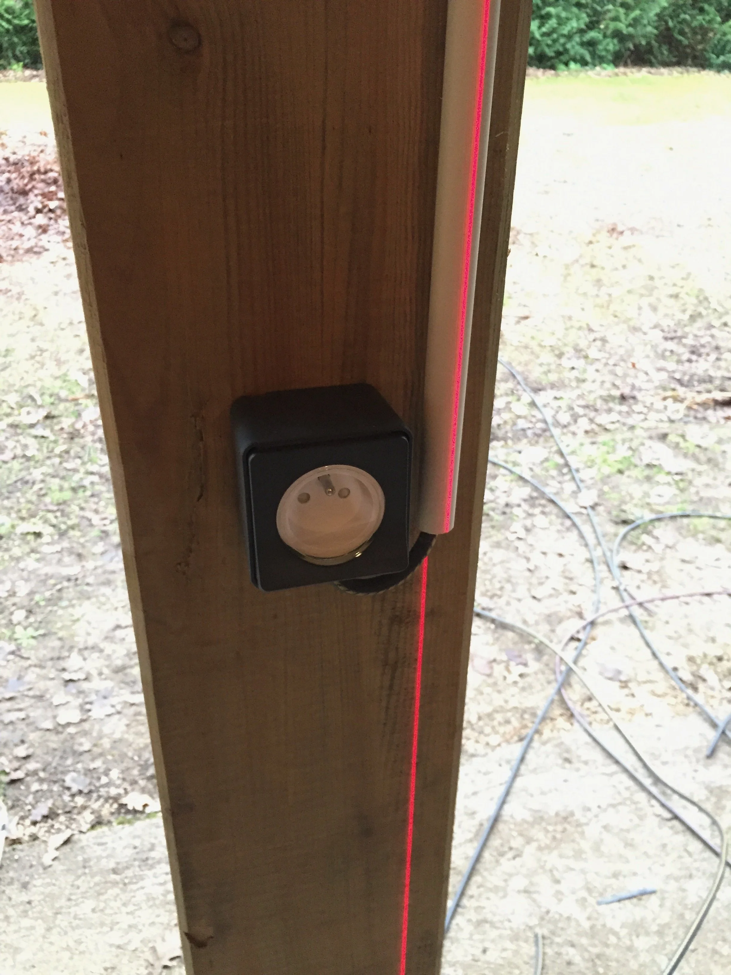 Prise électrique avec un laser rouge projeté le long d'une surface verticale en bois.