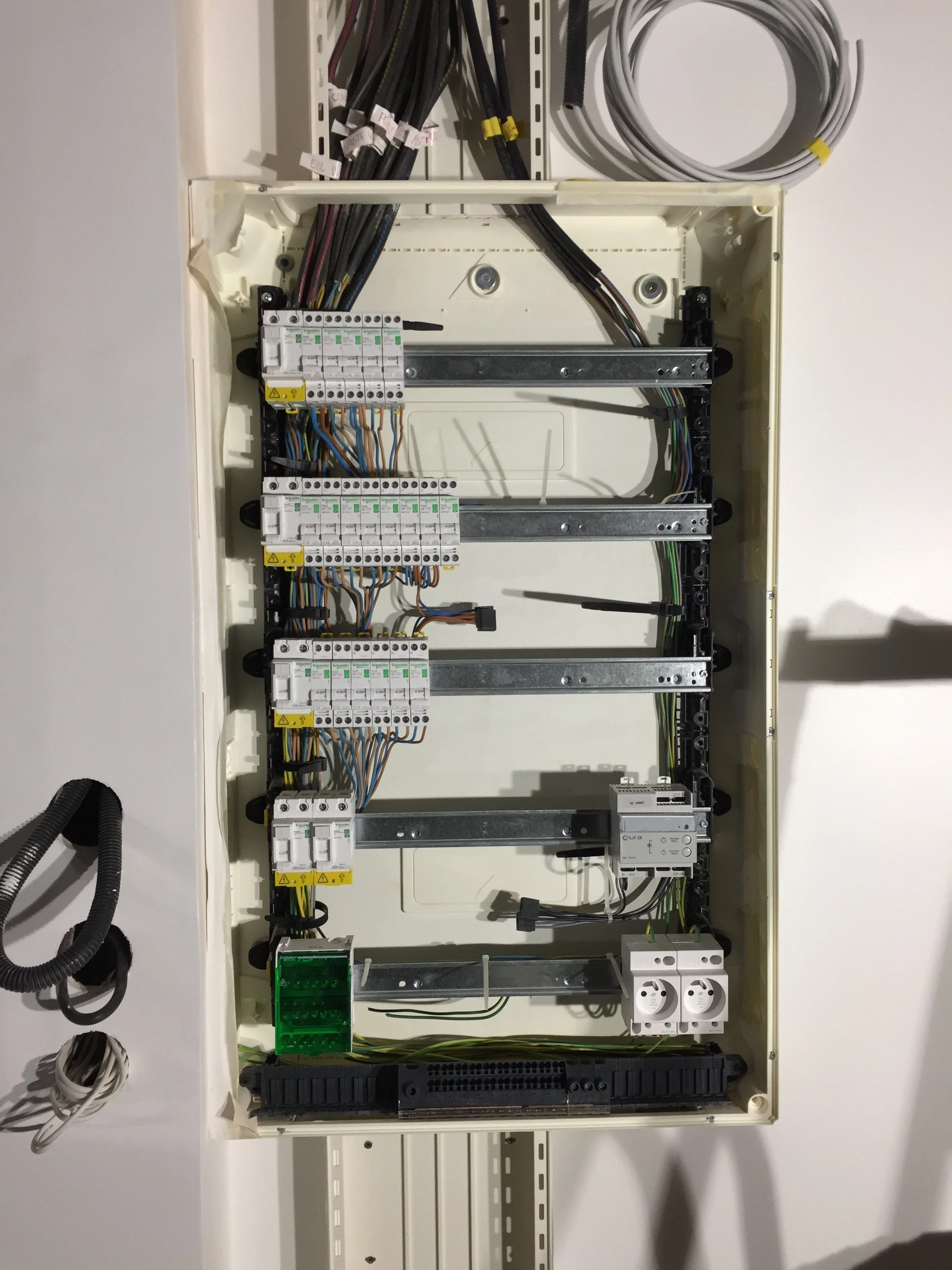 Un tableau électrique avec des disjoncteurs, câbles et composants électriques visibles.