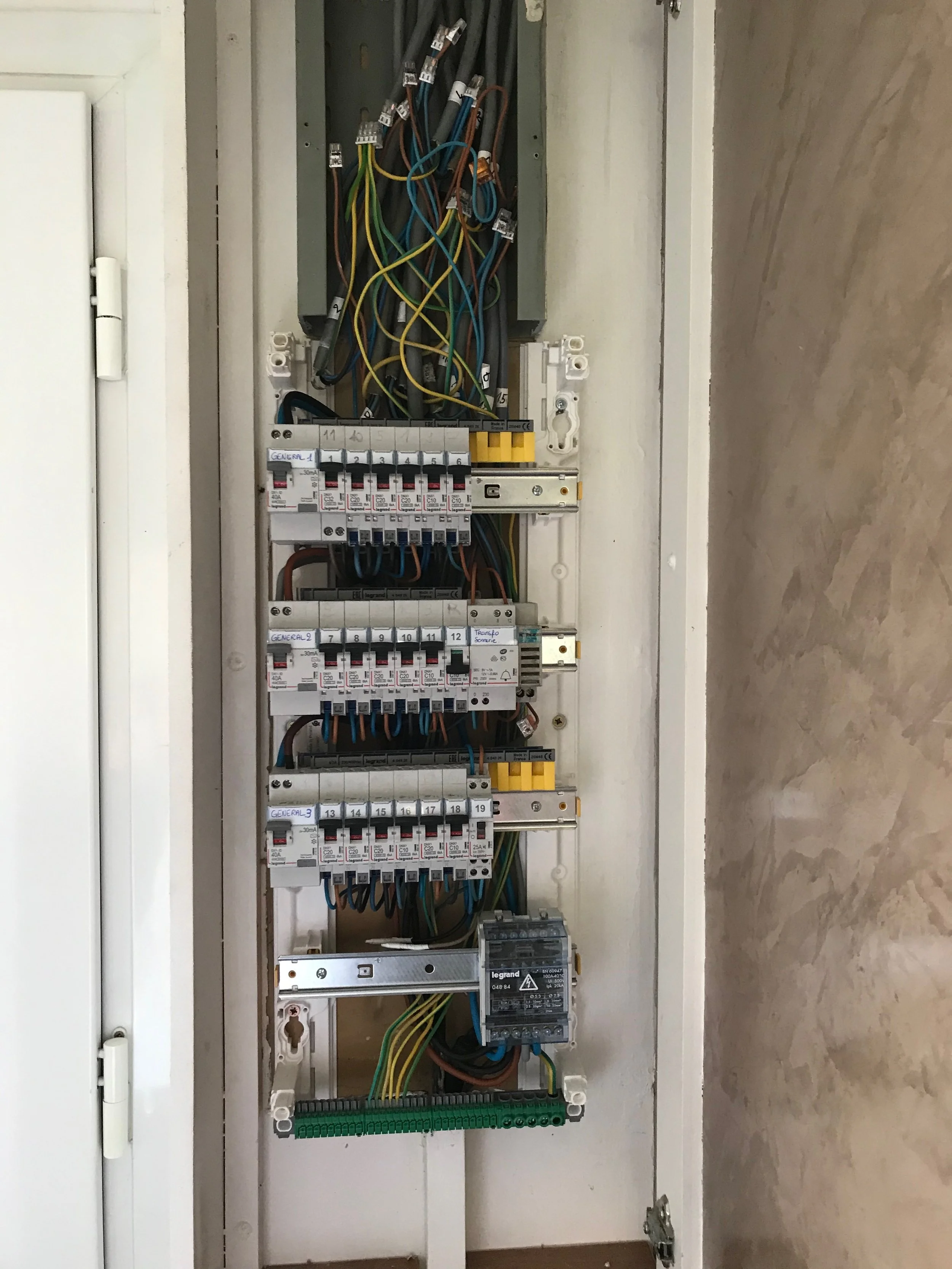 Panneau électrique avec divers câbles, disjoncteurs et composants électriques.