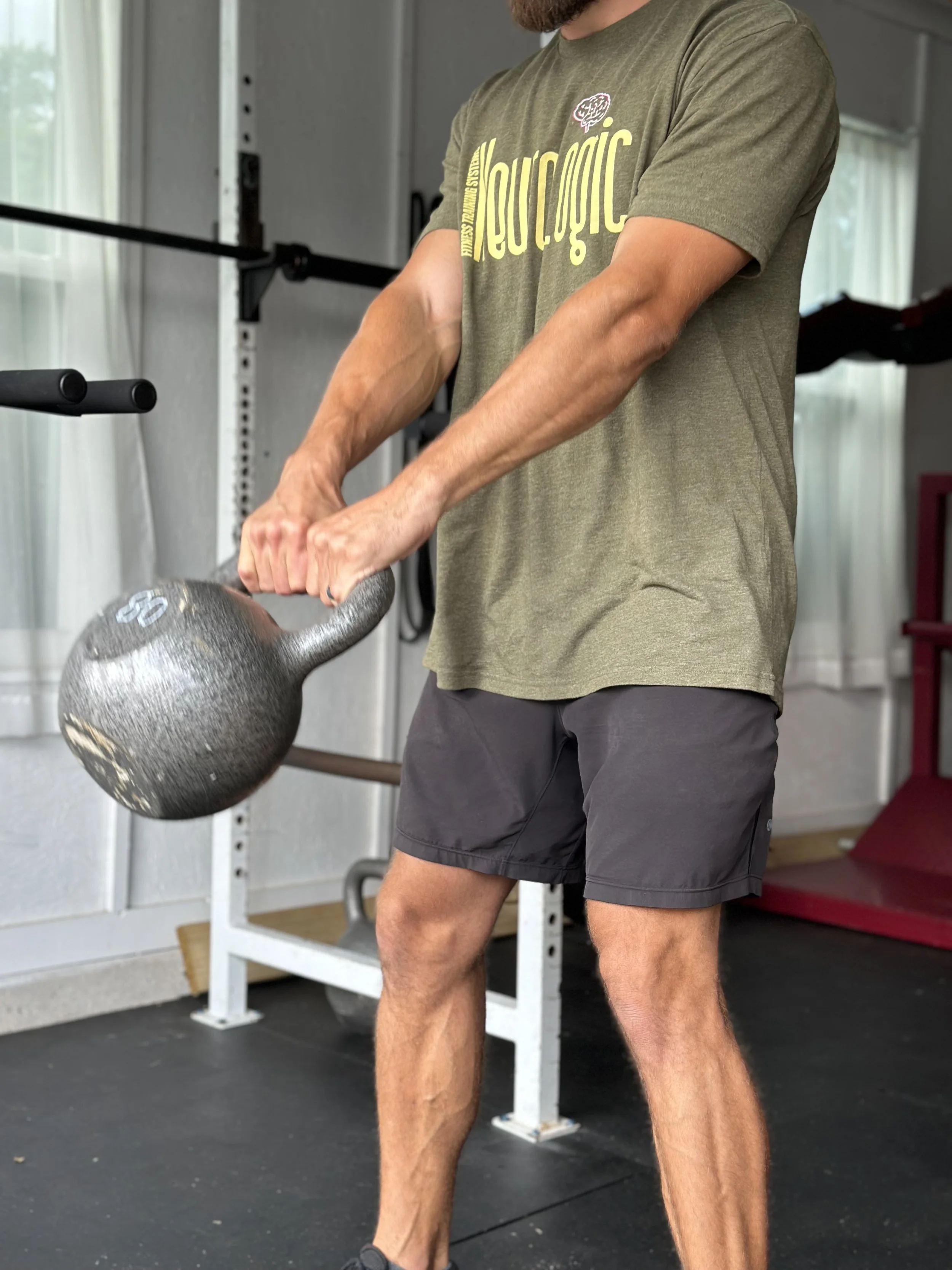 CEO of Neurologic Fitness Training Systems performing a kettlebell swing with a heavy weight focused on his hip hinge.