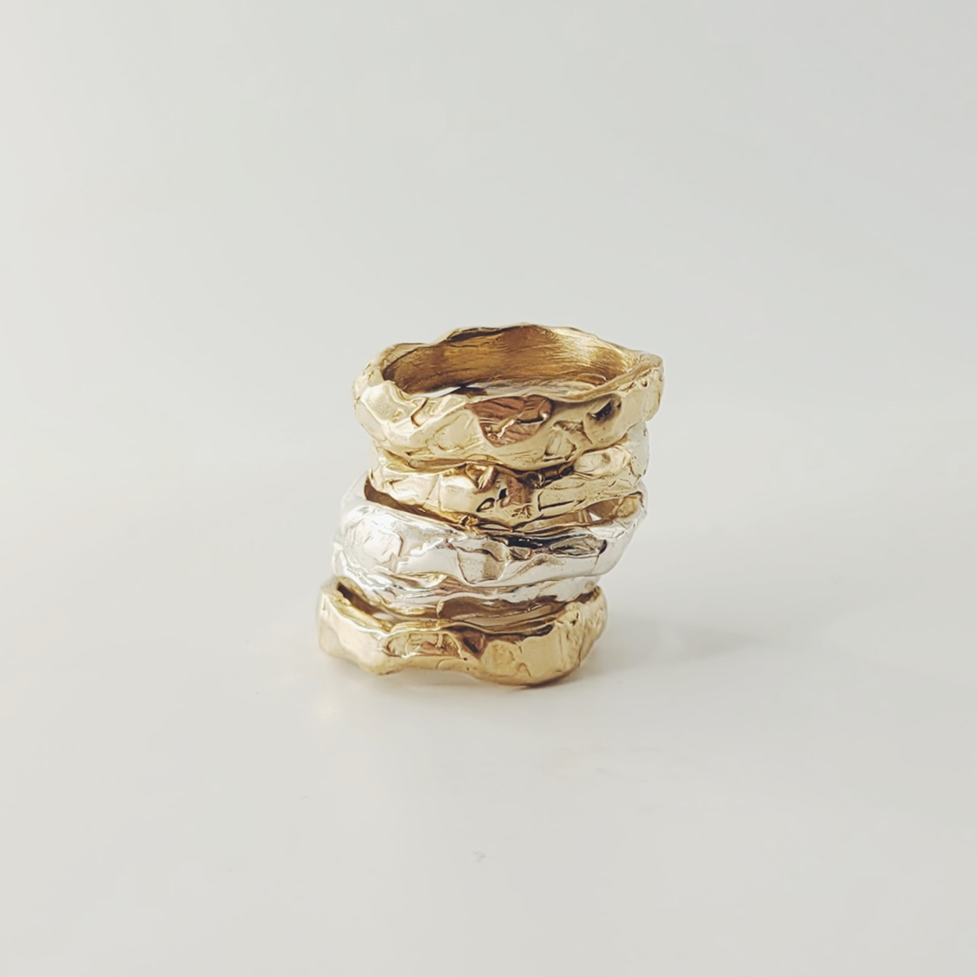 Quatre bagues empilées en métal, possibly en or ou en silver, sur fond blanc