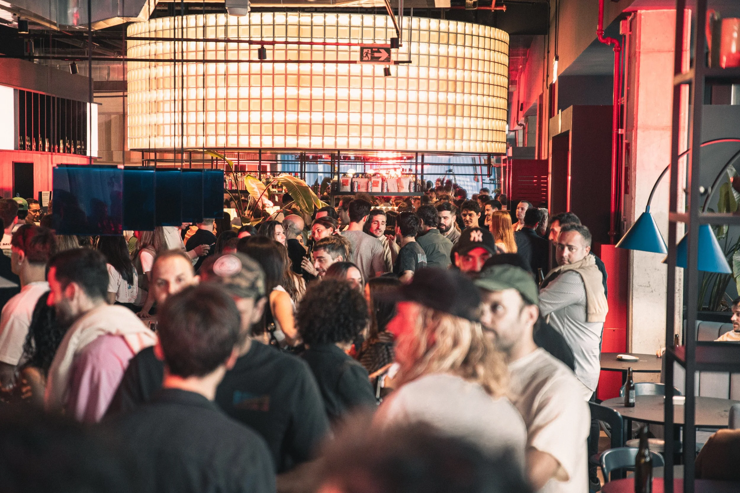 Mucho gente en un espacio interior concurrido, probablemente un restaurante o un bar, con iluminación cálida y decoración moderna.