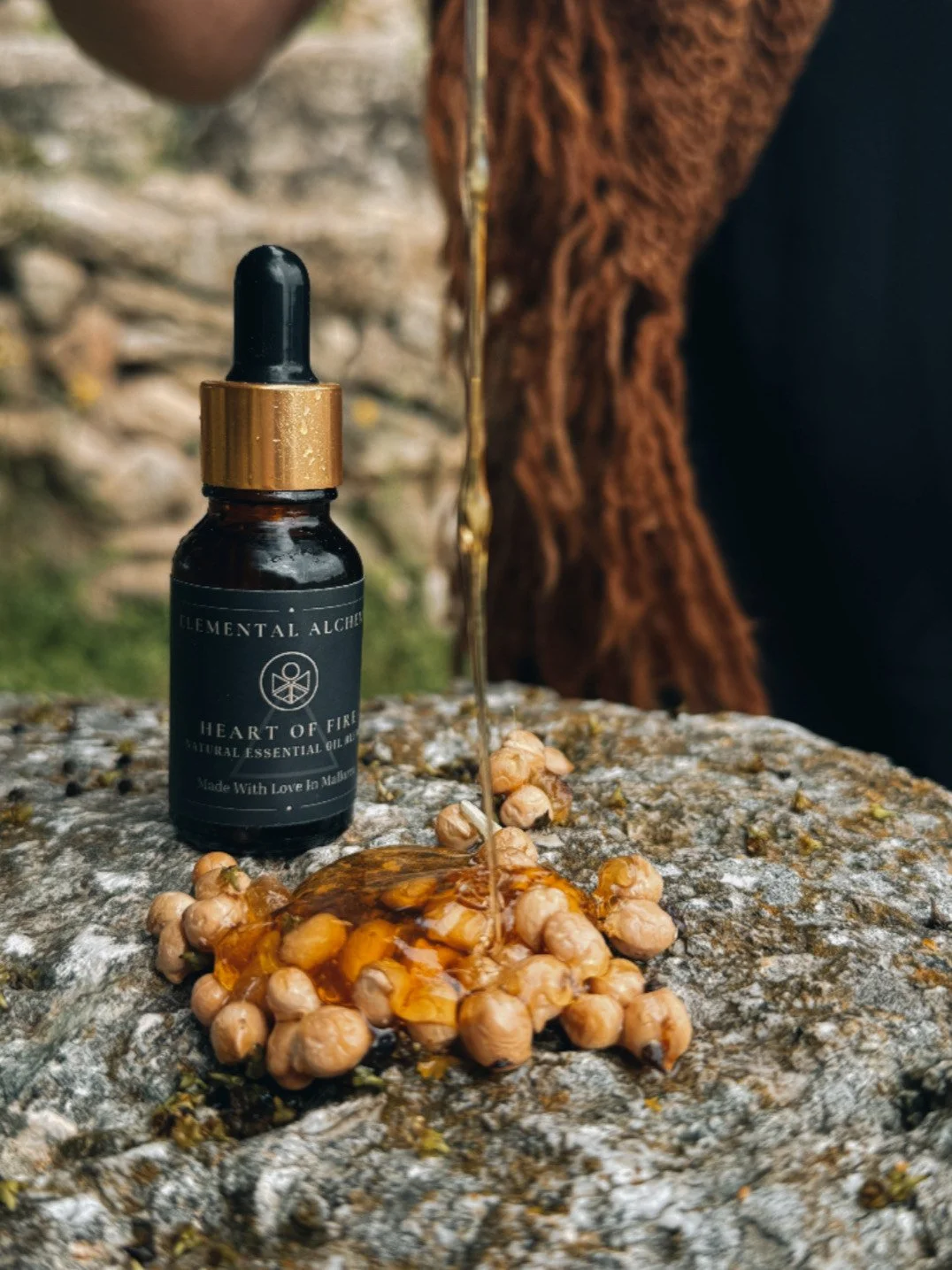 essential oil bottle labeled 'Heart of Fire' with honey and chickpeas on a rock outdoors.