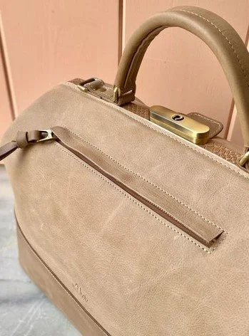 Close-up of a beige custom handbag with a zipper pocket and a handle.