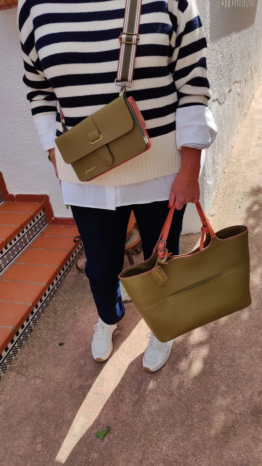 Close-up of a black Françoise Fondant leather handbag with red inside, showing pockets inside that can be closed with metal zippers. 