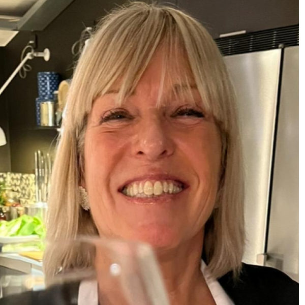 A woman with blonde hair smiling widely in a restaurant or bar area.