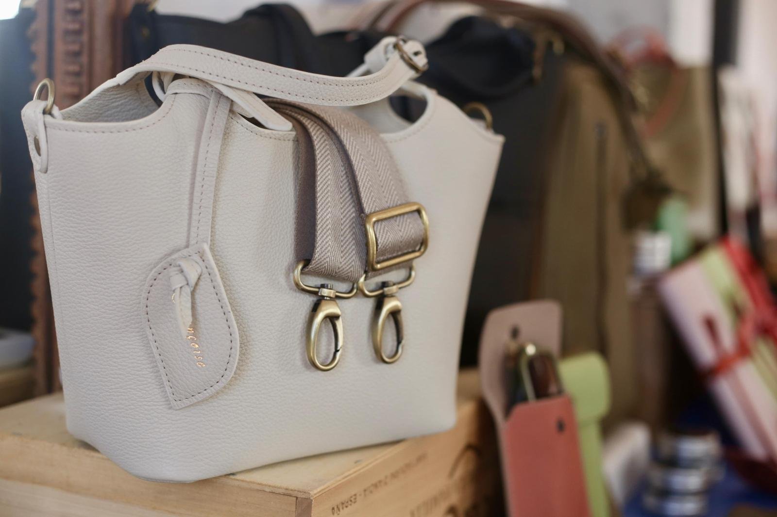A beige Francoise Noisette leather handbag with a beige leather strap and a mtaching canvas belt. 