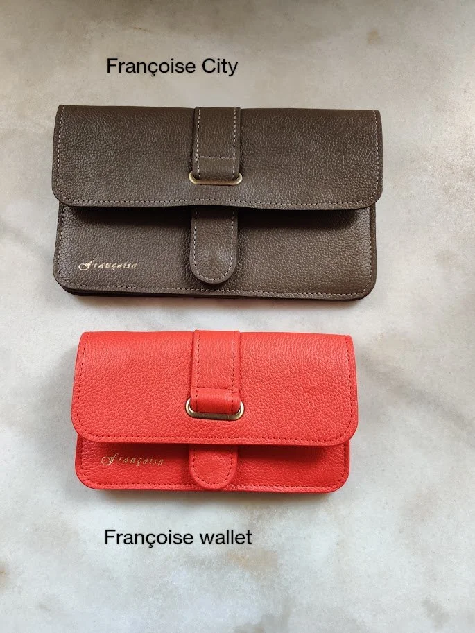 A black city bag and a red wallet. Both are made of leather, placed on a marble surface. 