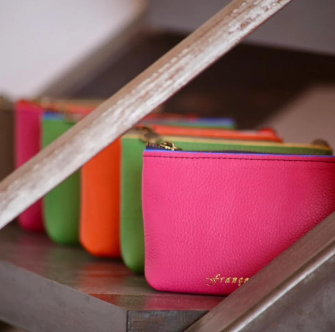 Close-up of colourful mini wallets on a wooden shelf.