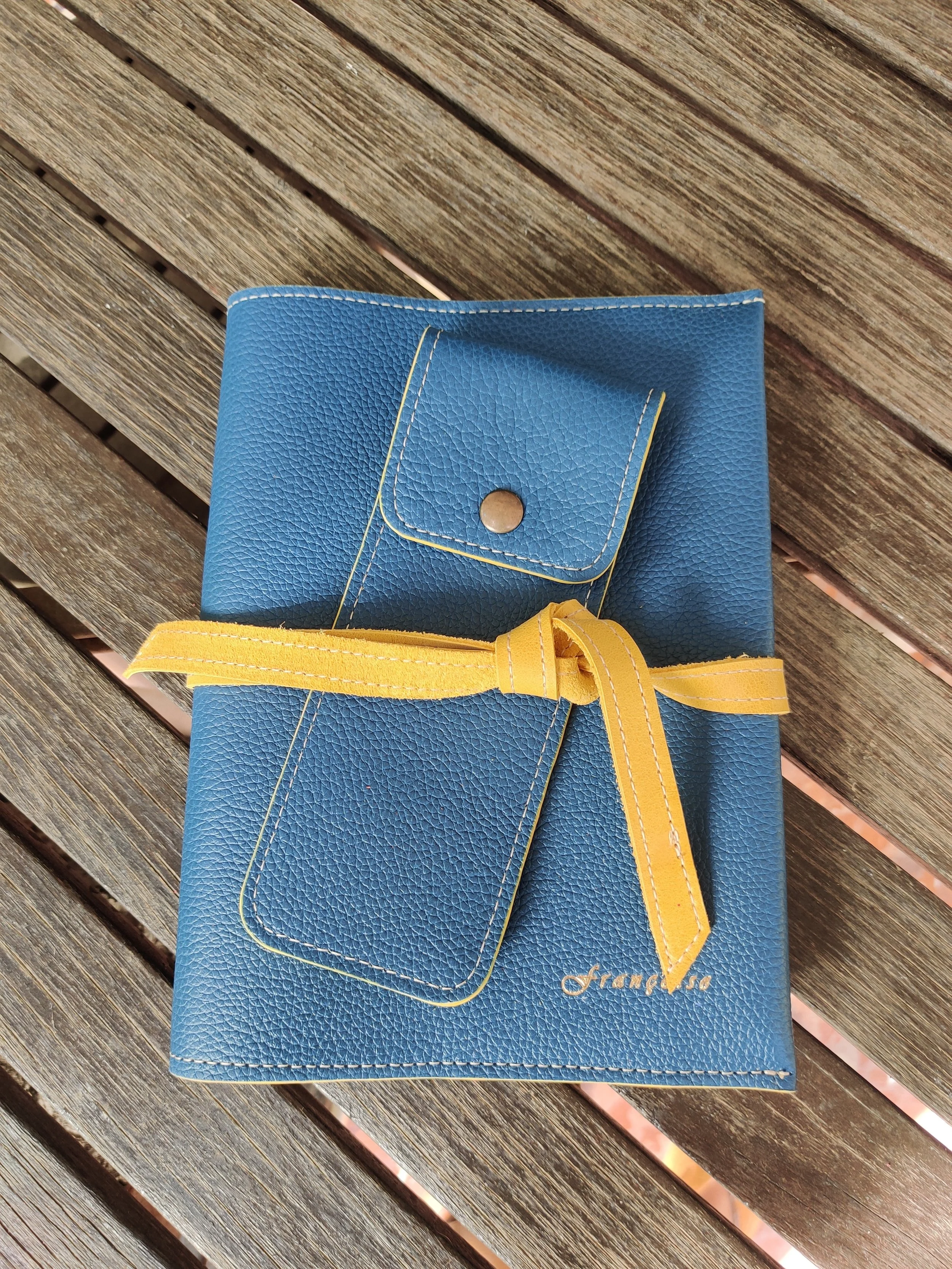 Blue leather notebook with a yellow leather ribbon, on a wooden surface.