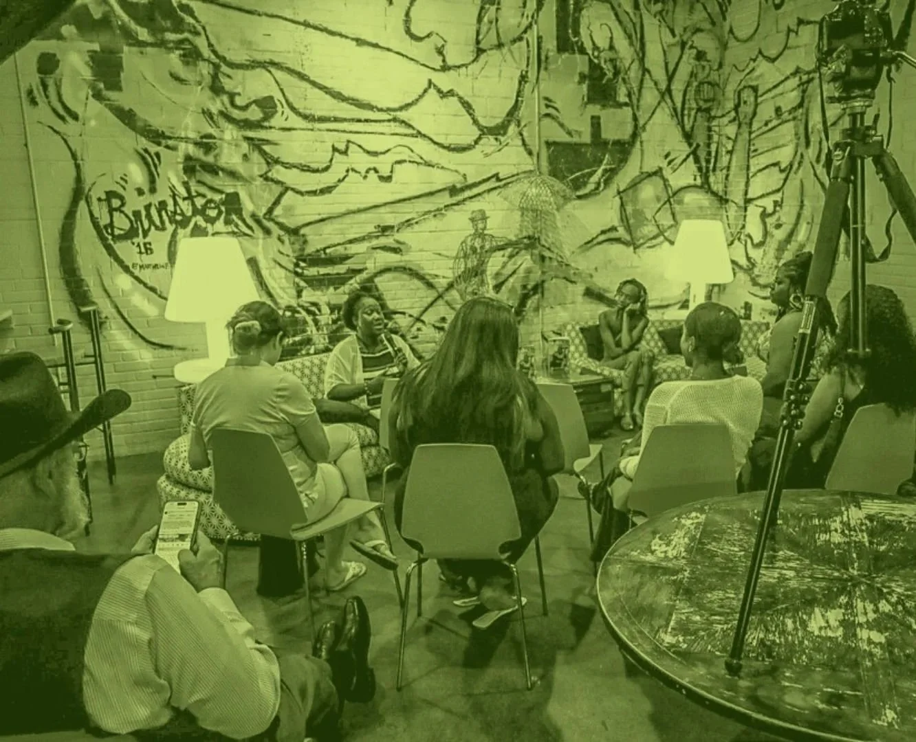 A group of people seated at a Sit With Me event, listening intently to the discussion.