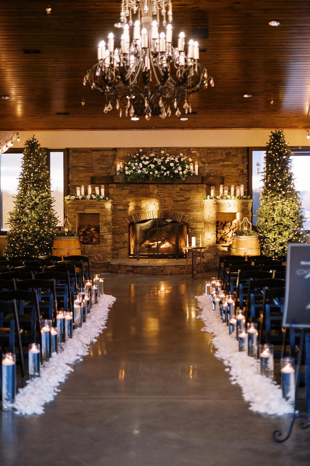 Wedding ceremony setup with a fireplace, Christmas trees, and candles, decorated for a winter celebration.
