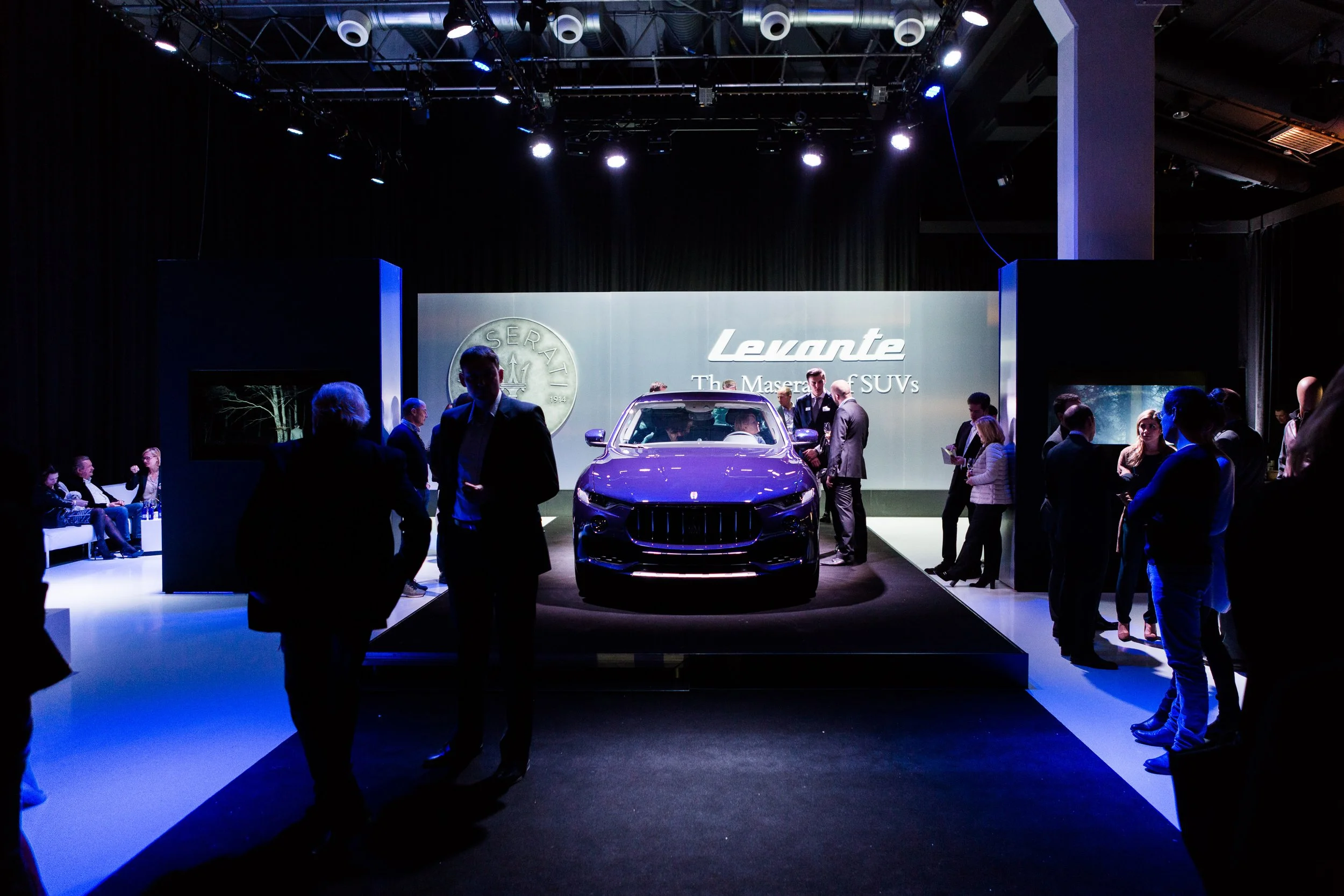 Auto-Präsentation auf einer Messe mit Publikum und heller Bühne, im Hintergrund ein großer Bildschirm mit dem Logo "Levante" und der Beschreibung "The Maserati SUV".