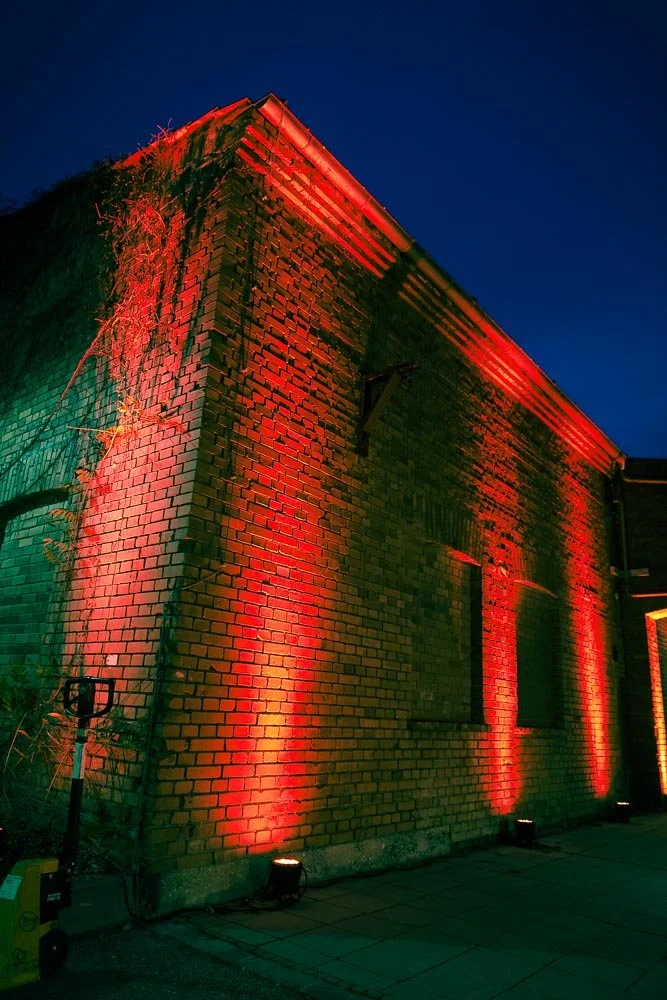 Ein Backsteingebäude ist nachts mit roten und grünen Lichtern beleuchtet.