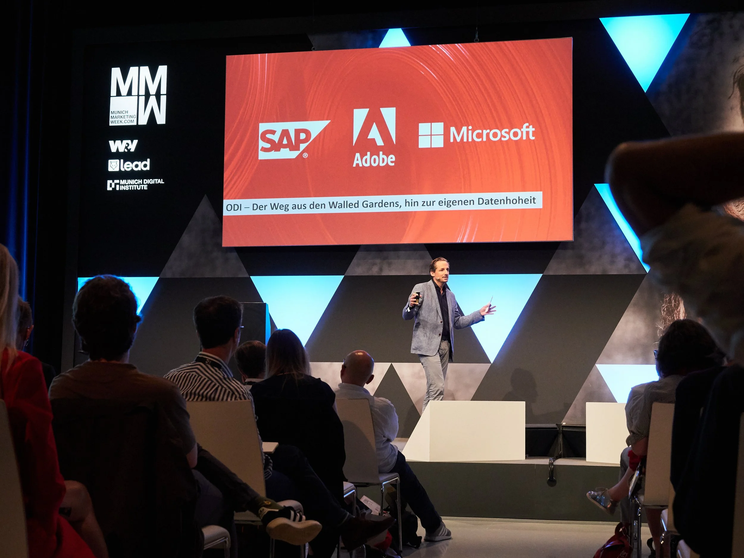 Präsentation auf der Marketing Messe mit Logos von SAP, Adobe und Microsoft, ein Redner spricht vor Publikum, Thema: Datenhoheit und Überwindung der Wall Gardens.